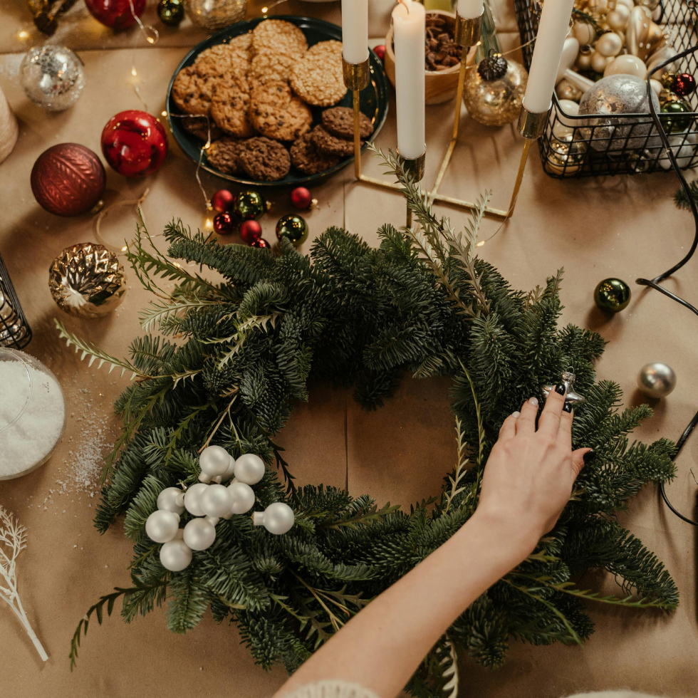 Auf dem Bild wird ein Adventkranz geschmückt, am Tisch ist Weihnachtsdeko zu sehen