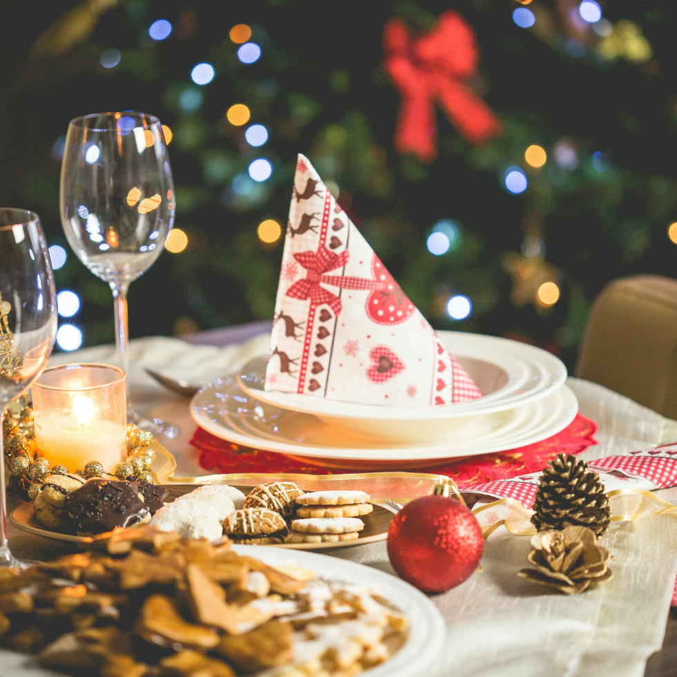 Am Bild ist ein gedeckter Tisch zu sehen mit einer Serviette, Gläser und Weihnachtsdeko.