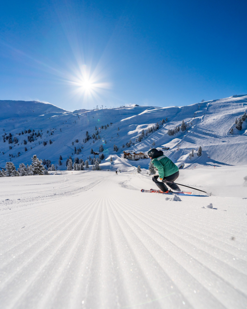 Ein Skifahrer am Wildkogel fährt bei Sonnenschein auf weißem, glitzerndem Schnee