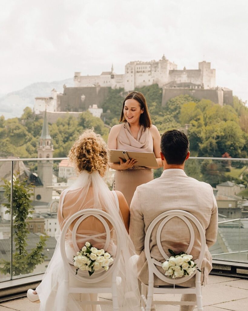 Hochzeitsrednerin Corinna Abele hält ihre Rede für ein Hochzeitspaar. Im Hintergrund sieht man die Festung Hohenwerfen in Salzburg