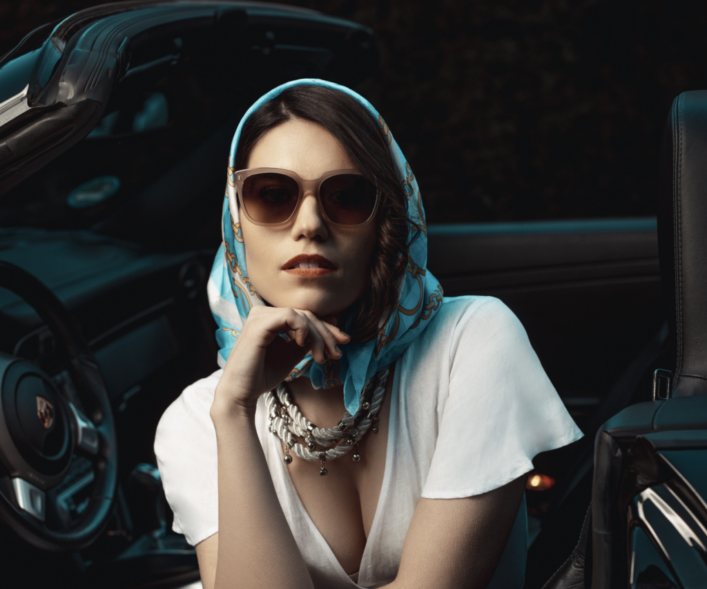 Brillenwerkstatt Roland Pföss: Ausschnitt einer Frau mit Sonnenbrille, die in einem Cabrio posiert