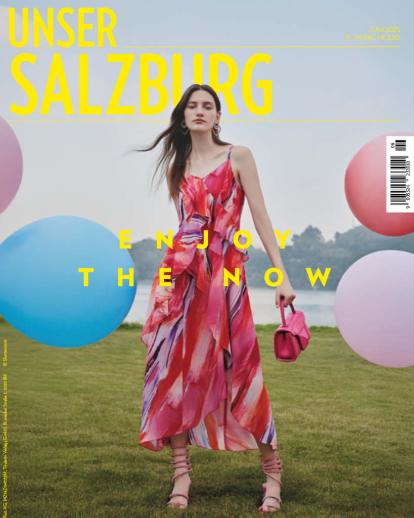 Unser Salzburg Cover Juni 2025: Frau mit rotem Kleid, dahinter bunte Ballons