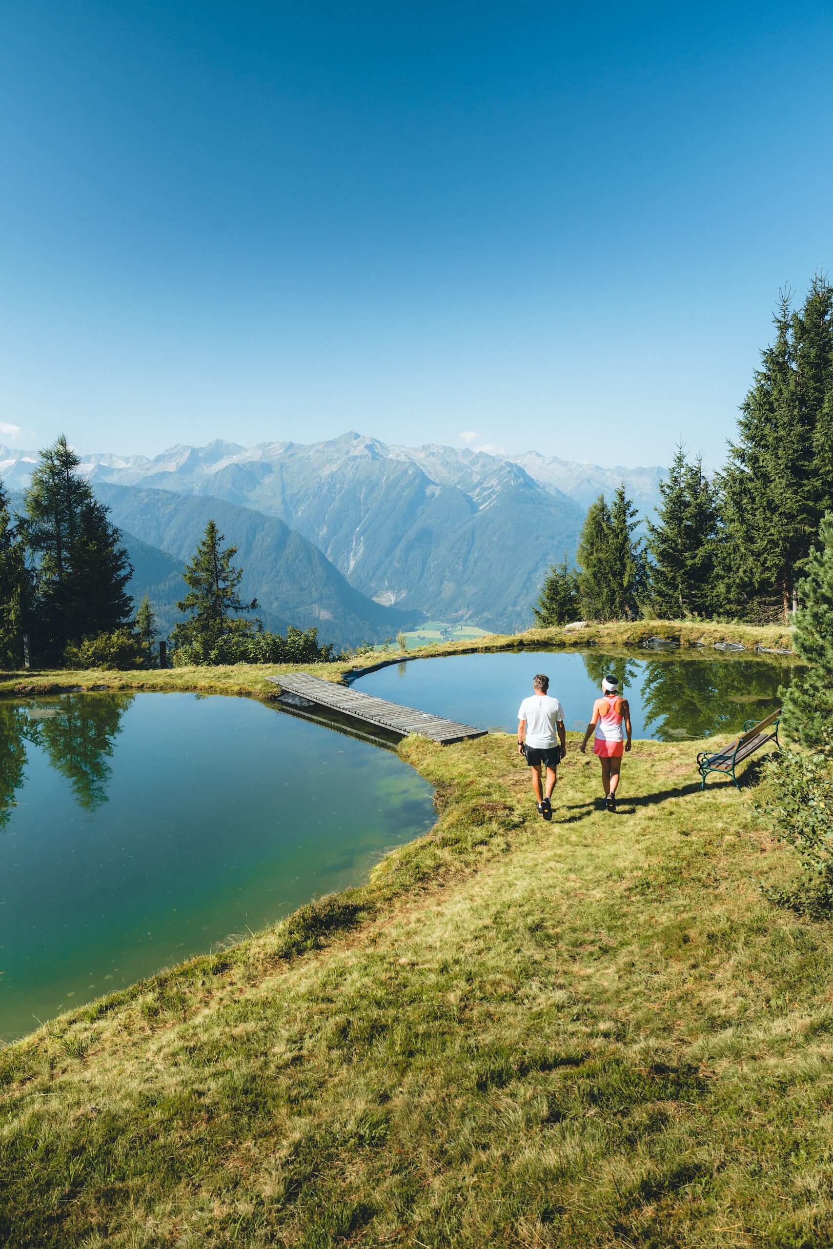 Wildkogel-Arena Neukirchen & Bramberg, Ein Pärchen wandert entlang eines Sees mit Bergpanorama