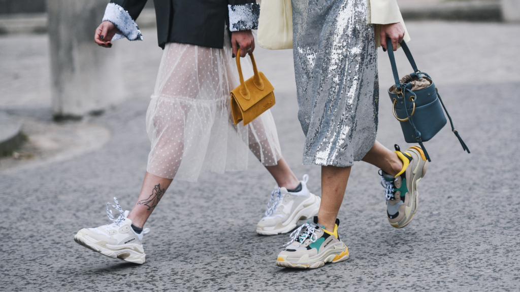 Tirolerin Outfit-Ideen, Thema Röcke, zwei Frauen gehen in stylischen Outfits der Straße entlang, detaillierte Aufnahme, Sneaker, Sporty Spice