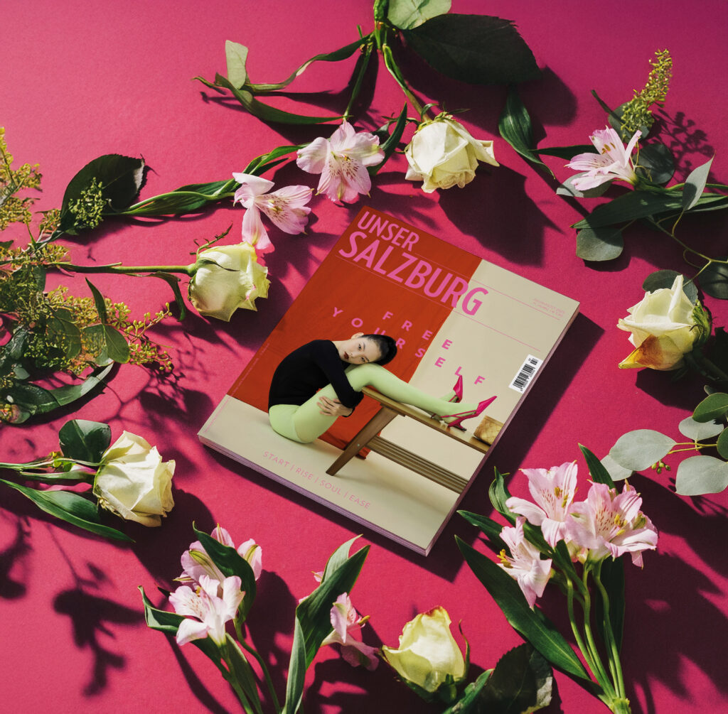 Unser Salzburg, die Sommerausgabe vor einem pinken Hintergrund und Blumen