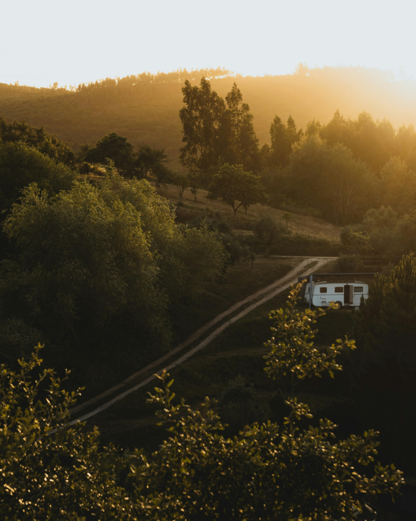 Wald und Wiesen Landschaft mit Sonnenuntergang, rechts im Bild ein weißer Camper