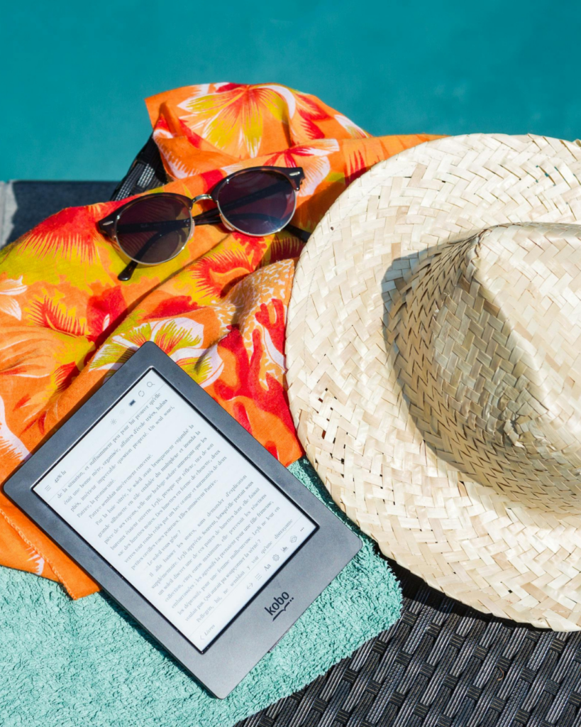 Lese-Tablet, Sonnenhut und Sonnenbrille - im Hintergrund Pool