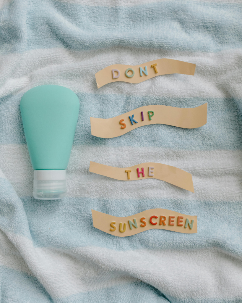 Auf einem Handtuch liegt eine Sonnencreme und rechts daneben steht: Don't skip the Sunscreen