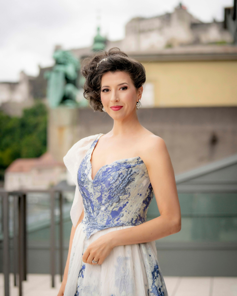 Salzburger Festspiele: Stück Maria Stuarda - mit einer der Darstellerinnen im eleganten Kleid, im Hintergrund verschommen die Festung Hohensalzburg