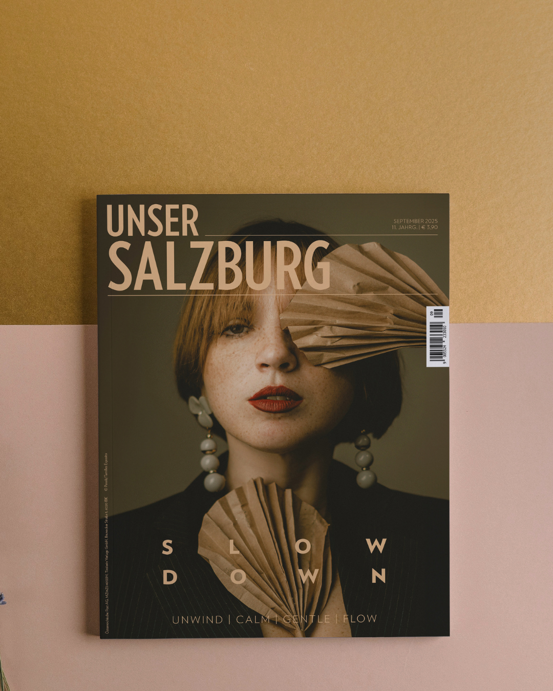Cover der Unser Salzburg September-Ausgabe, Titel: Slow Down, am Bild eine Frau mit kurzen, rötlichen Haaren und zwei Fächern