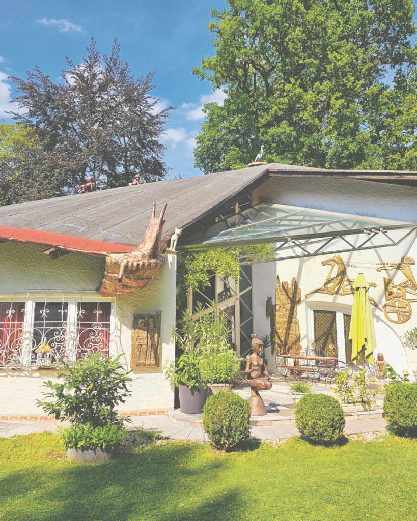 "Das Schneckenhaus" - Bild eines Hauses mit verschiedensten Verzierungen, Schnecke am Dach, Statuen