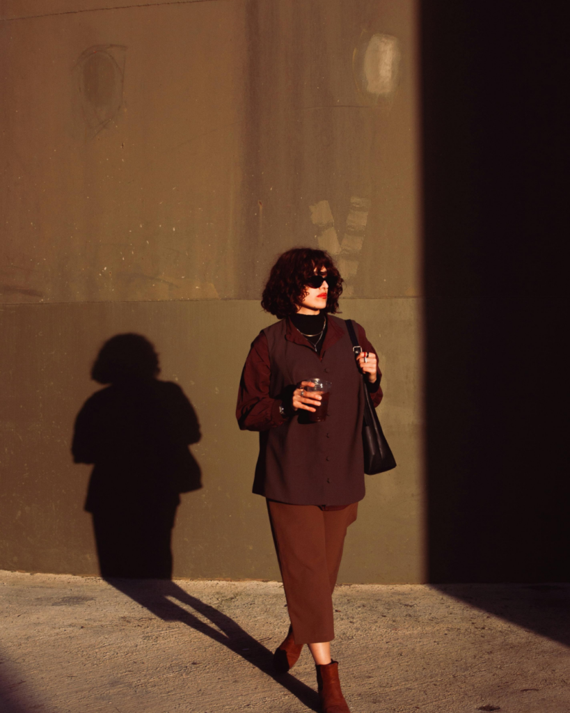 Brauner Hintergrund, Frau mit braunen Outfit und Kaffee in der rechten Hand