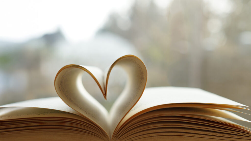 Liebe: Heart from page of book for valentine's day concept with blurred bright light background and vintage tone.