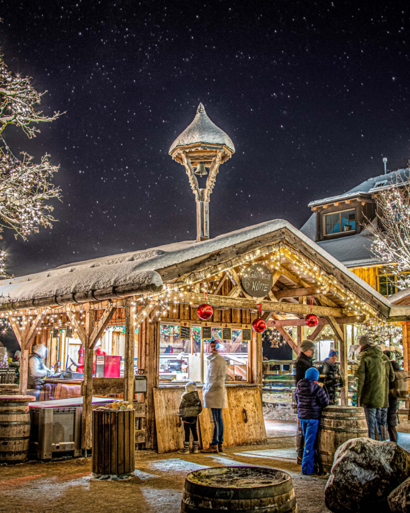 Adventmarkt Gut Aiderbichl in Salzburg, leuchtender Marktstand - Glühweinhütte