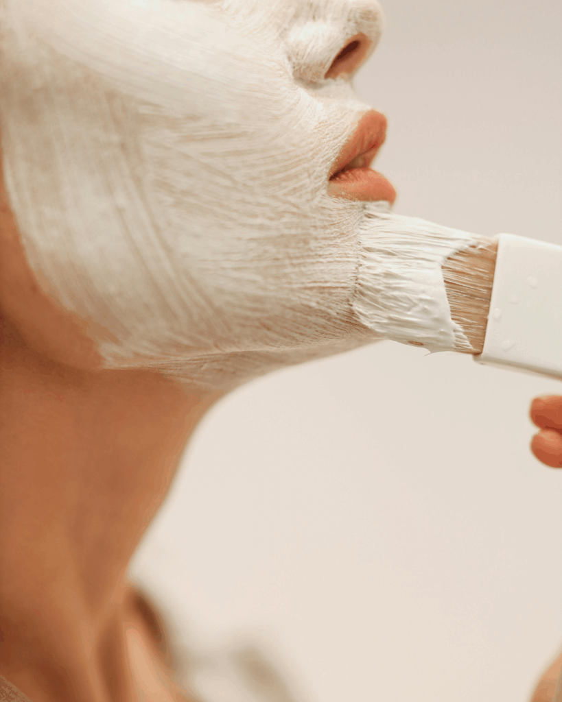 Eine Frau, die Gesichtsmaske mit einem Pinsel aufträgt