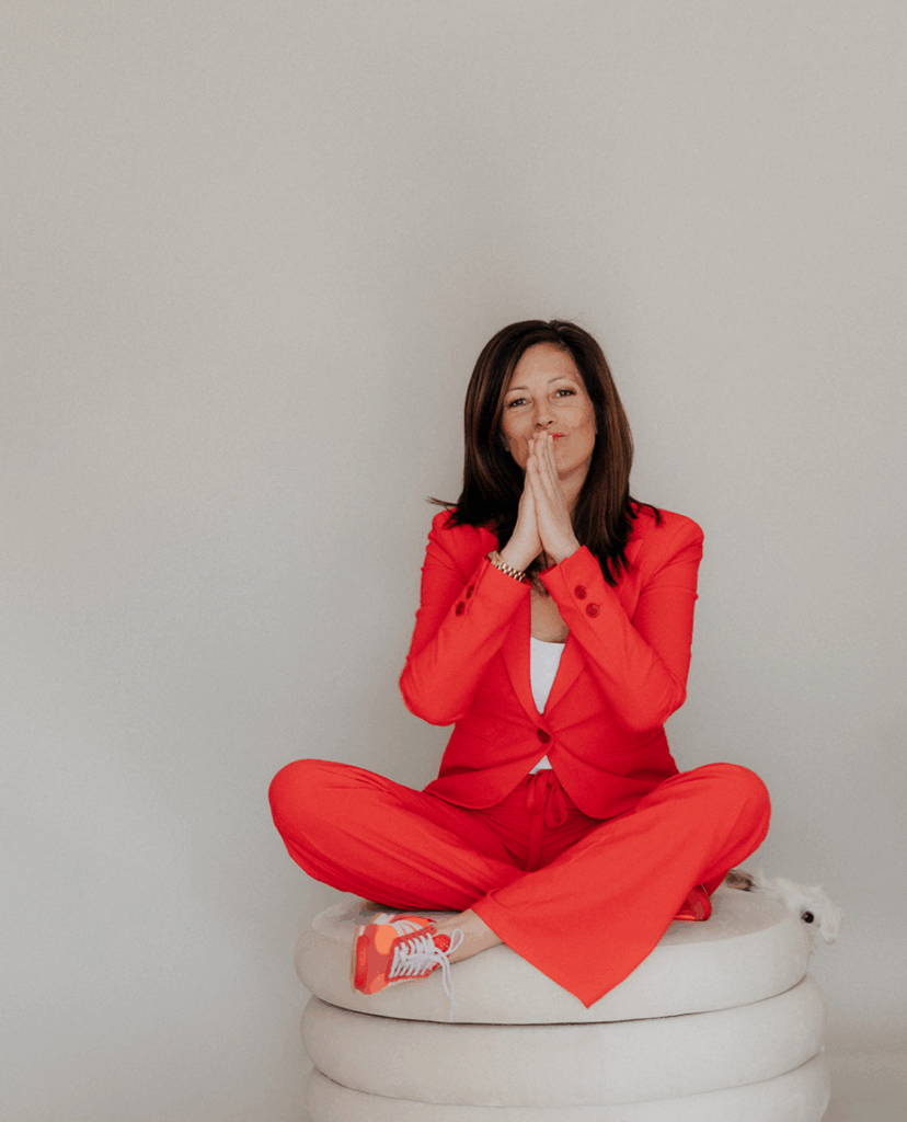 Portraitbild von Silvia Faulhammer in rotem Anzug, sitzend und gefaltete Hände vor Gesicht