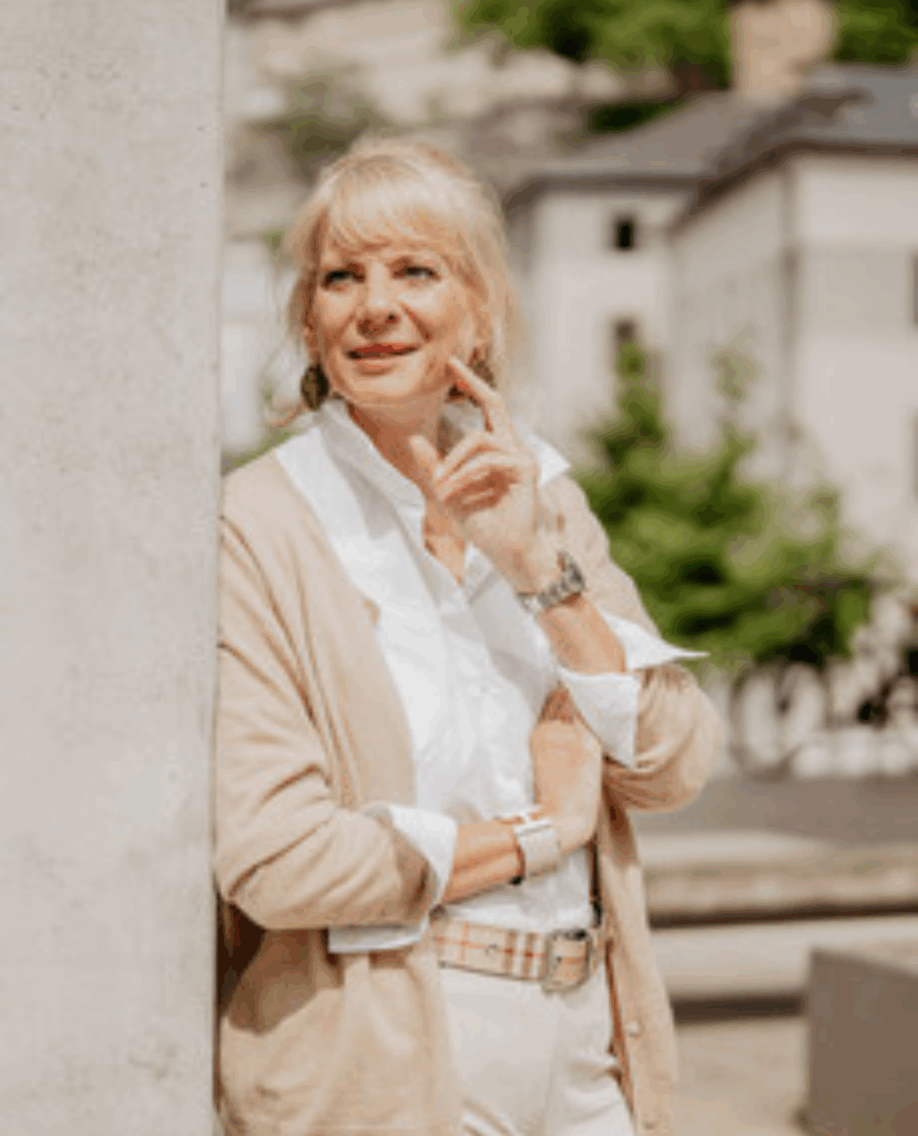 Dr. Sabine Viktoria Schneider im Portraitbild, sie lehnt an eine Wand mit der linken Hand im Gesicht als Pose