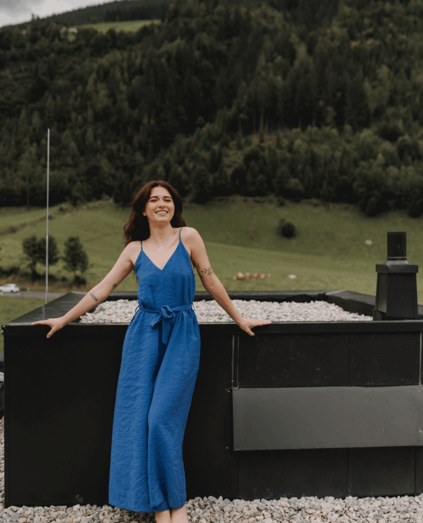 Im Bild: Influencerin Steffi Harms in blauem Jumpsuit, lacht in die Kamera