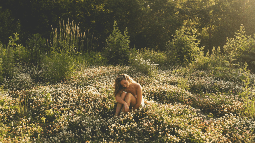 Eine Frau sitzt in einer Blumenwiese