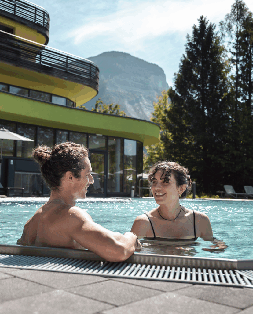 Ein Pärchen im Pool, das lacht und sich ansieht