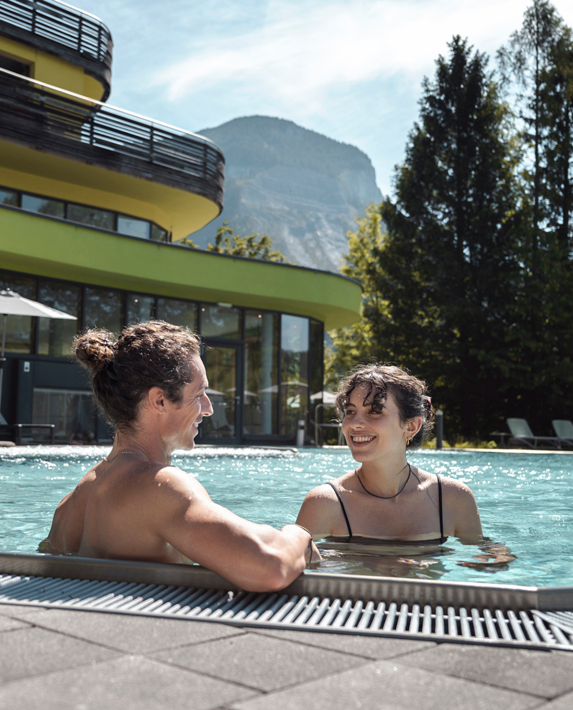 Ein Pärchen im Pool, das lacht und sich ansieht