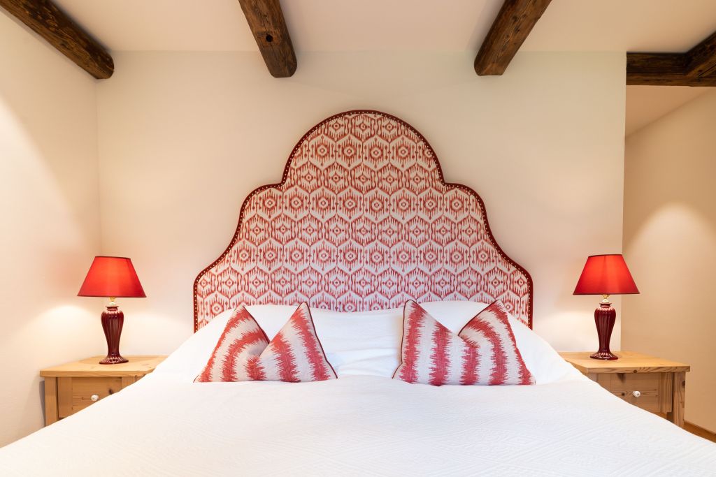 Ein Bett der Tischlerei Huber mit roten Details wie Polster und Lampenschirme