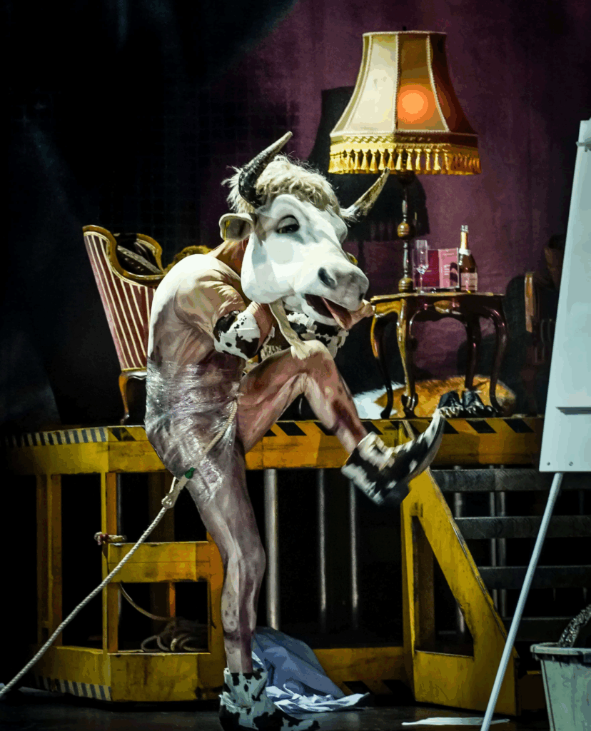 Ein Schauspieler mit einer Kuhmaske und Cowboystiefel