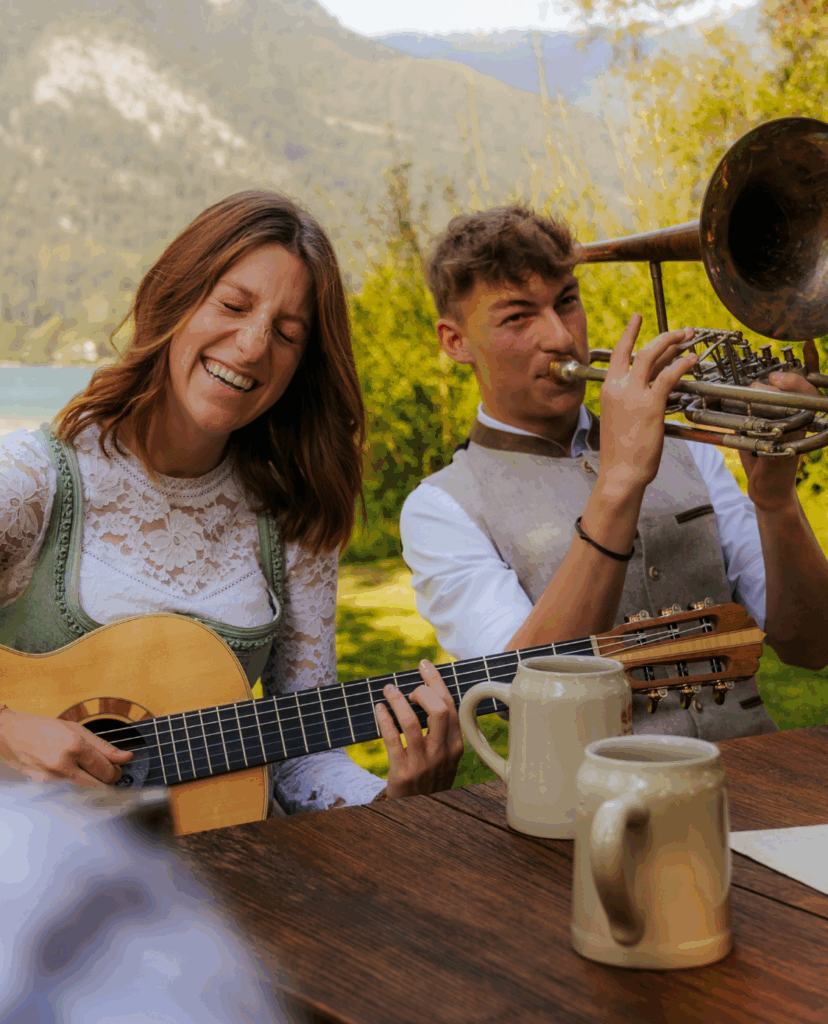 Eine Frau und ein Mann in Tracht, die mit Gitarre und Blasinstrument fröhlich musizieren
