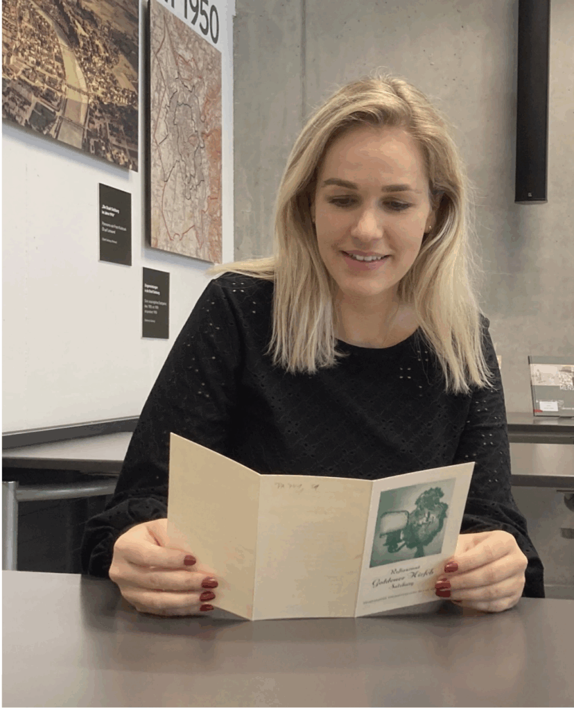 Alexandra Embacher hält eine alte Speisekarte in der Hand